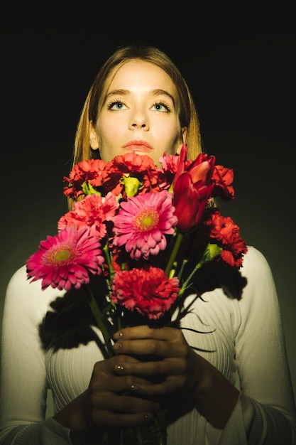 Free photo thoughtful woman with bright flowers bouquet