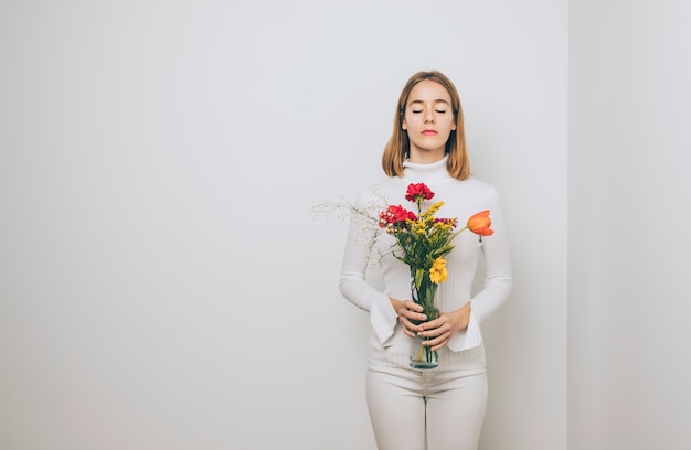 Thoughtful woman with bright flowers in vase