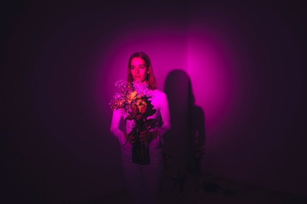 Thoughtful woman with flowers in vase 