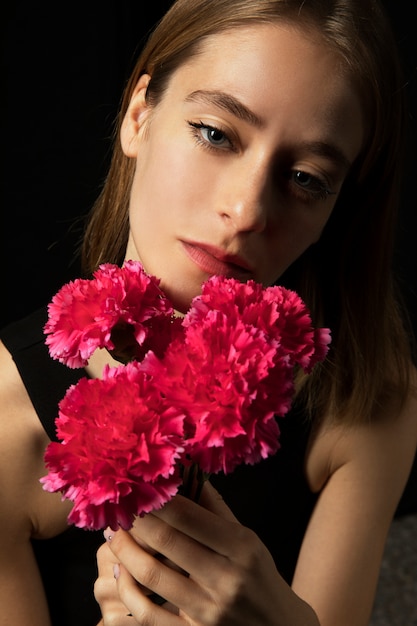 Free photo thoughtful woman with pink carnations