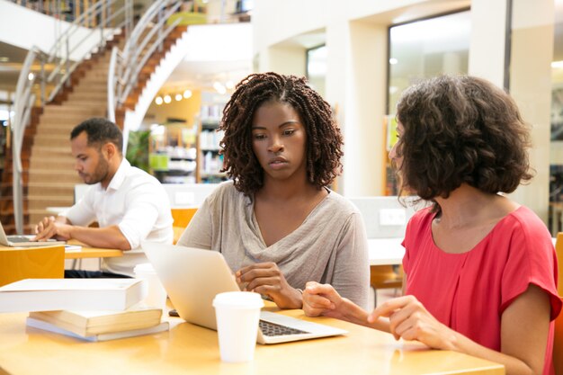 Thoughtful women using laptop at library