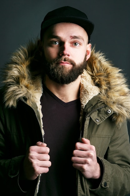 Thoughtful young man in parka with fur hood 