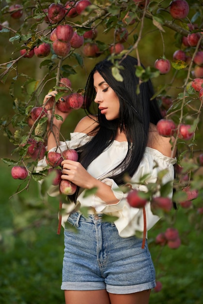 Free photo thoughtful young woman posing in apple orchard