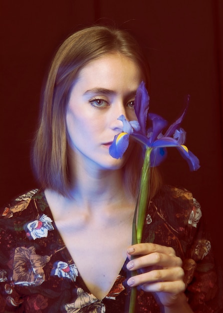 Free photo thoughtful young woman with blue flower