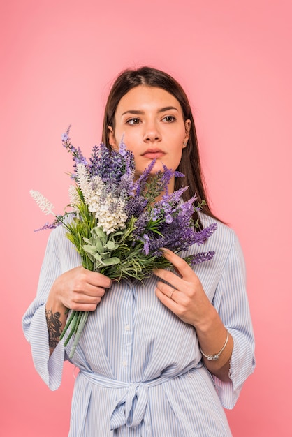 Free photo thoughtful young woman with flowers bouquet