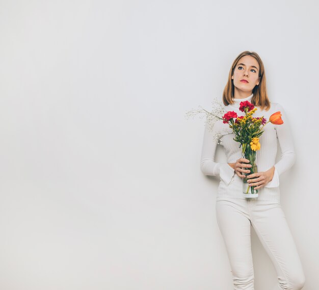 Thoughtful young woman with flowers in vase