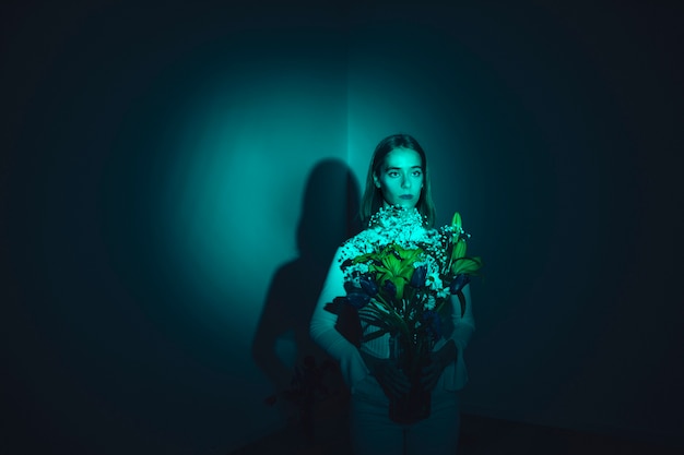 Free Photo thoughtful young woman with flowers in vase 