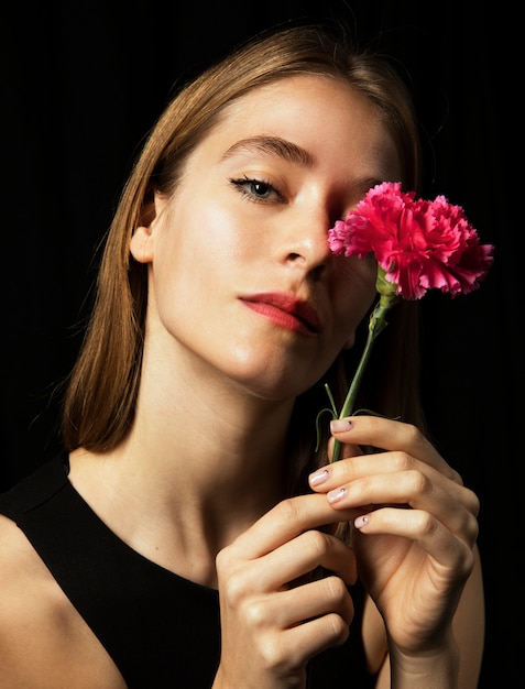 Thoughtful young woman with pink carnation