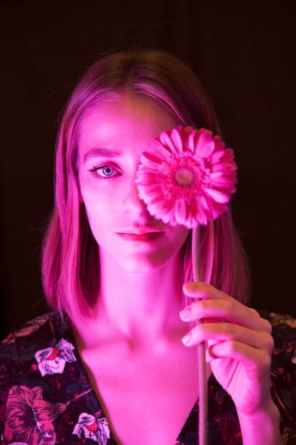 Thoughtful young woman with pink gerbera