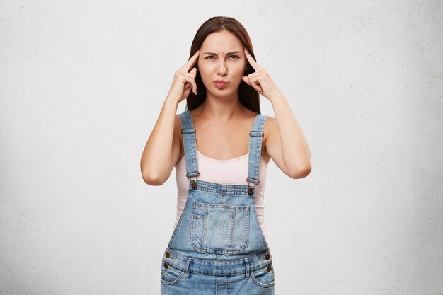 Thoughts, concentration and focus concept. Picture of funny young Caucasian woman in stylish clothes having concentrated look