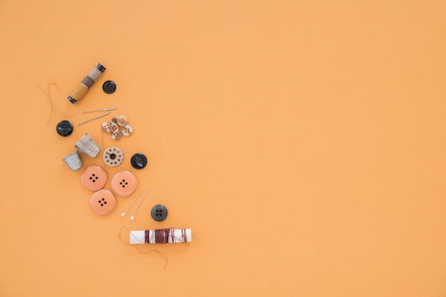 Thread; needle; thimble and various buttons on colored backdrop