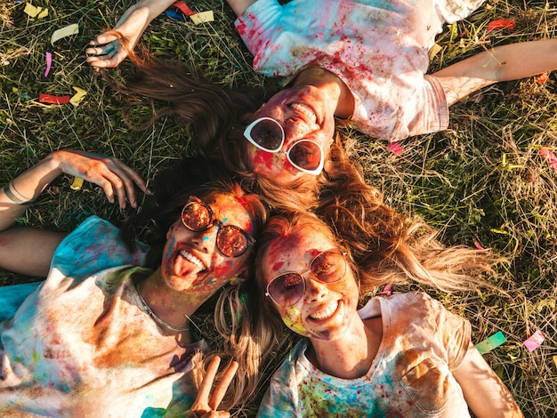 Free photo three beautiful smiling girls posing at holi party