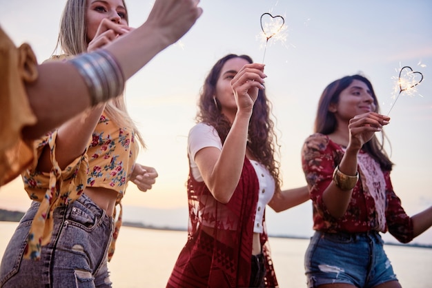 Three beautiful women having fun with sparklers on the beach