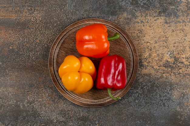 Three bell peppers in the board on the marble surface