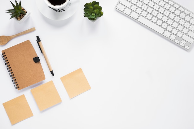 Three blank adhesive notes with diary; pen and keyboard on white background