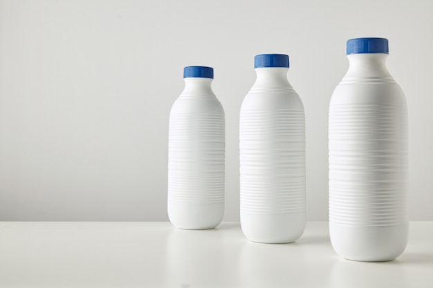 Free Photo three blank white plastic riffled bottles with blue caps in row isolated on table