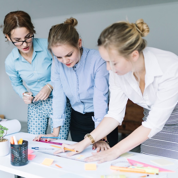 Free photo three businesswomen preparing business chart on desk in office