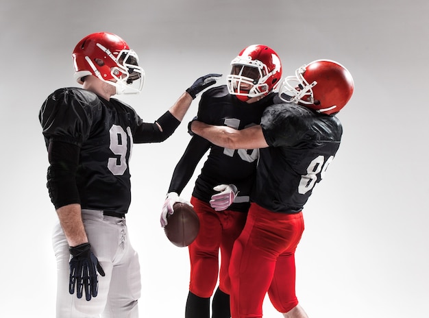 The three caucasian fitness men as american football players posing  as winners on white background and rejoicing