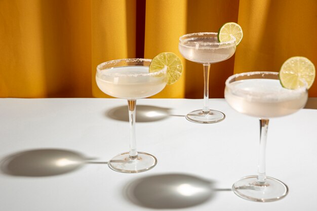 Three classic margarita drink with lime and salt in saucer glasses on table