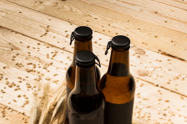 Free photo three closed beer bottles and ears of wheat on woodgrain