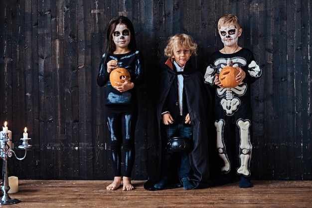 Free photo three cute kids in scary costumes during halloween party in an old house. halloween concept.