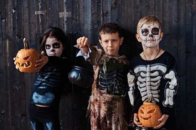 Free photo three cute kids in scary costumes during halloween party in an old house. halloween concept.