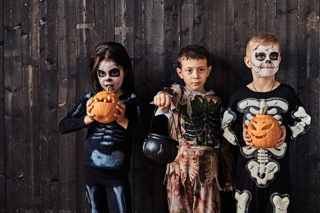 Free Photo three cute kids in scary costumes during halloween party in an old house. halloween concept.