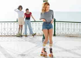 Free photo three female friends with roller skates rolling outdoors