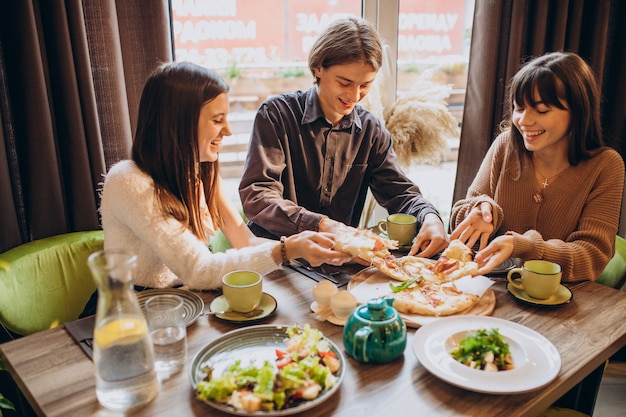 Free photo three firends together eating pizza in a cafe