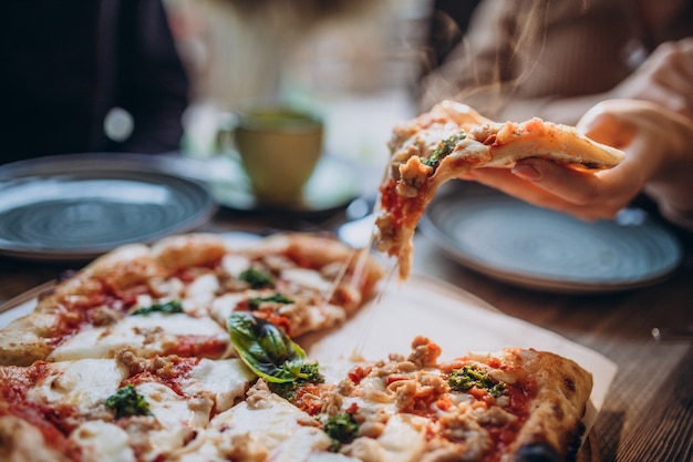 Three firends together eating pizza in a cafe