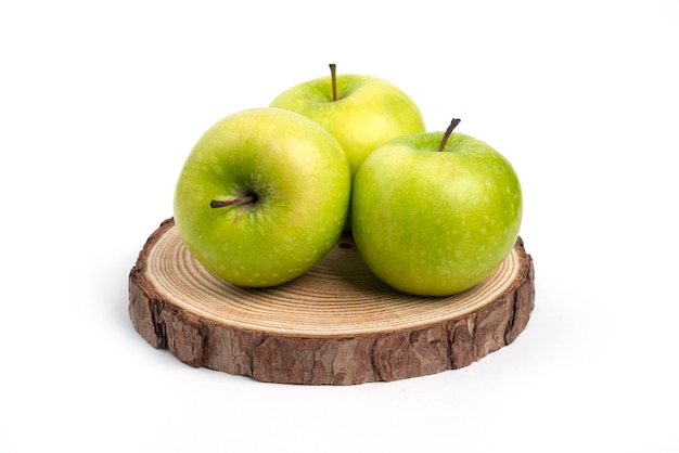 Three fresh apples on wooden piece.