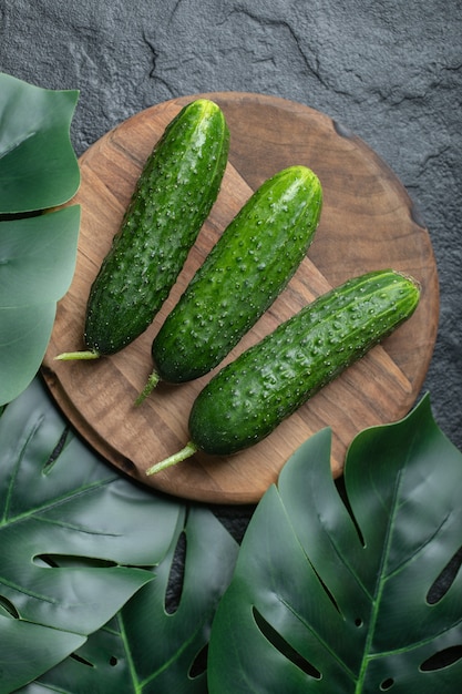 Three fresh cucumber on wooden board. Vertical photo. 