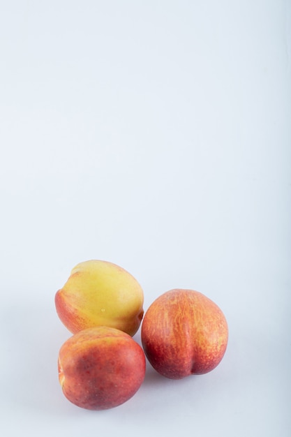 Free photo three fresh nectarines on white.