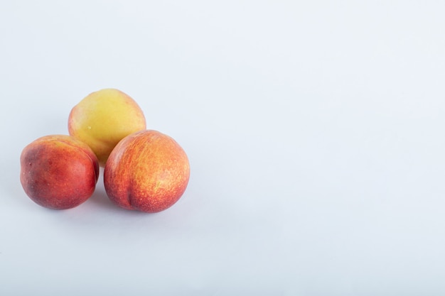 Three fresh nectarines on white.