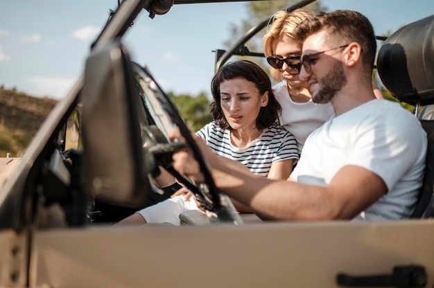 Free photo three friends checking map while traveling by car