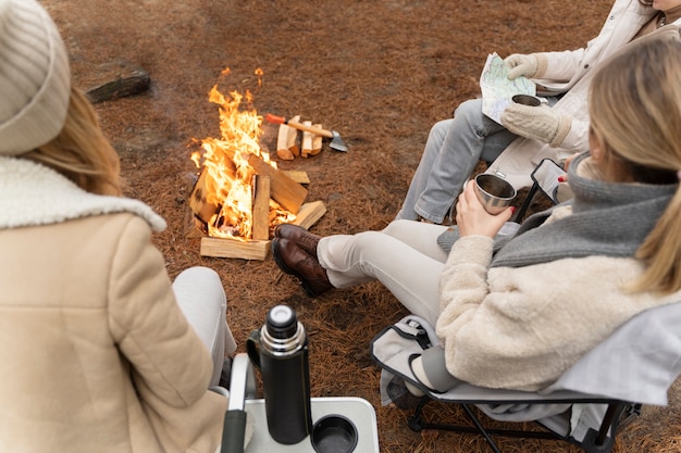 Free photo three friends drinking water and sitting by a bonfire