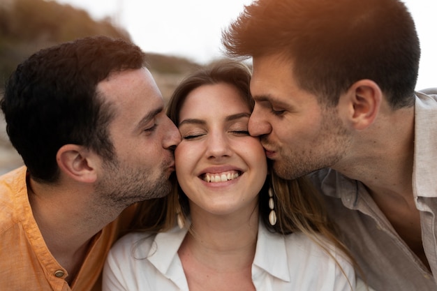 Three friends kissing while posing together during a beach party