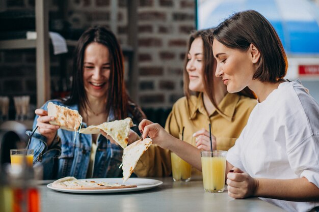 Three girl friends having pizza at a bar