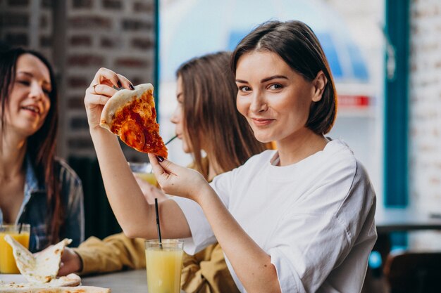 Three girl friends having pizza at a bar