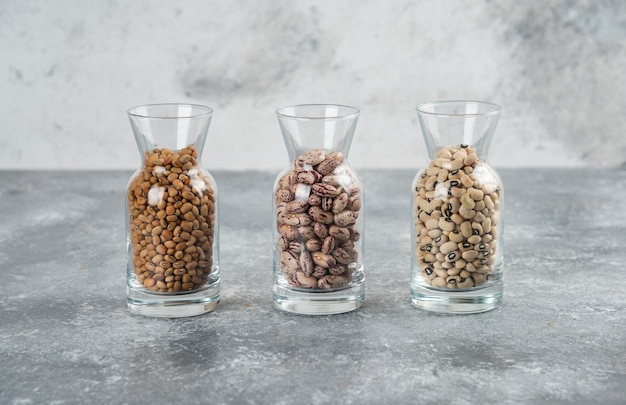 Free Photo three glasses of jar with unprepared beans on a gray table.