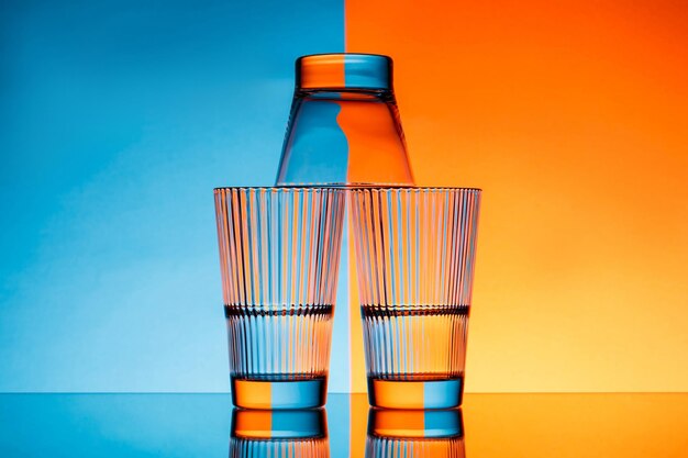 Three glasses with water on blue and orange