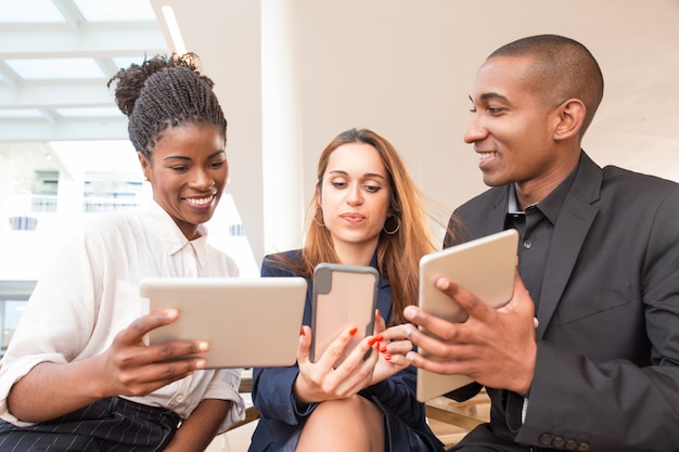 Free Photo three happy businesspeople using gadgets in office