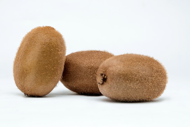 Three kiwi fruits on a white surface