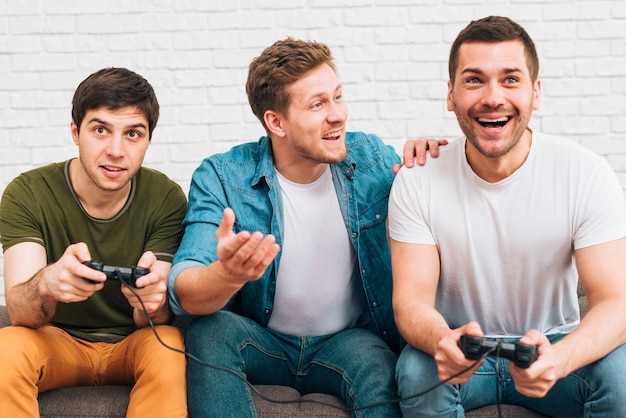 Three male friends sitting together enjoying the video game