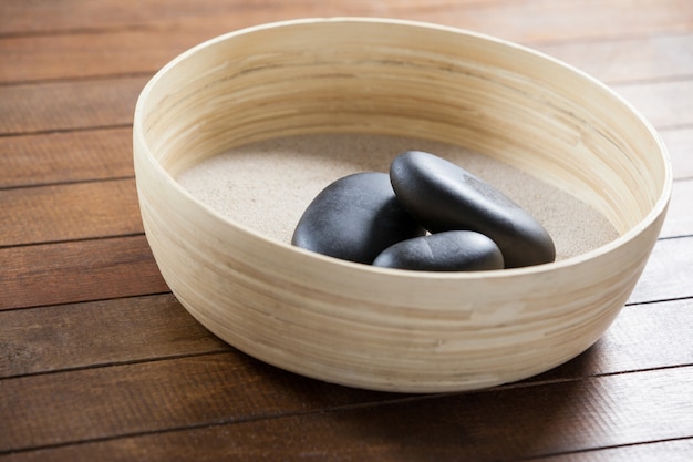 Three pebble stone on a wooden bowl