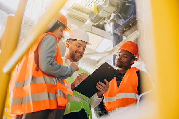 Free photo three people discussing a plan at a factory