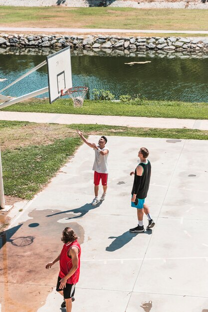 Three players looking at basketball falling from net