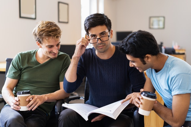 Three positive students studying together and drinking