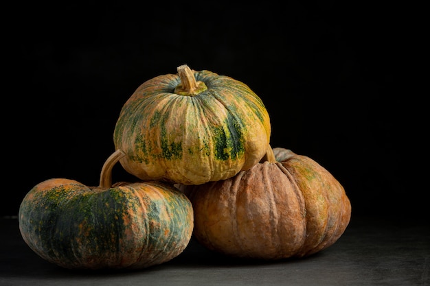 Three pumpkins placed on a dark floor