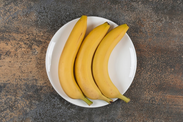 Free photo three ripe bananas on white plate